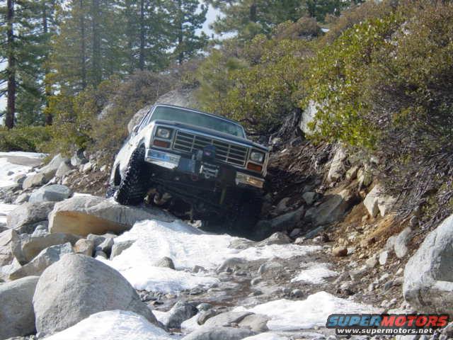 1986 Ford Bronco navigating a rocky, snowy trail