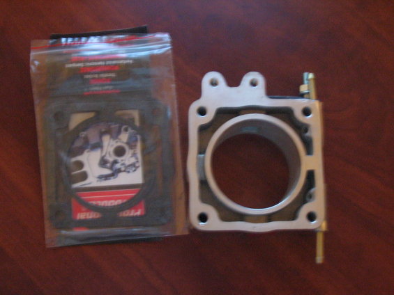 Throttle body and a package of gaskets on a wooden surface