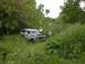 1994 Ford Bronco - This vintage SUV appears to be stuck in a field of tall grass, with two people looking under the hood.