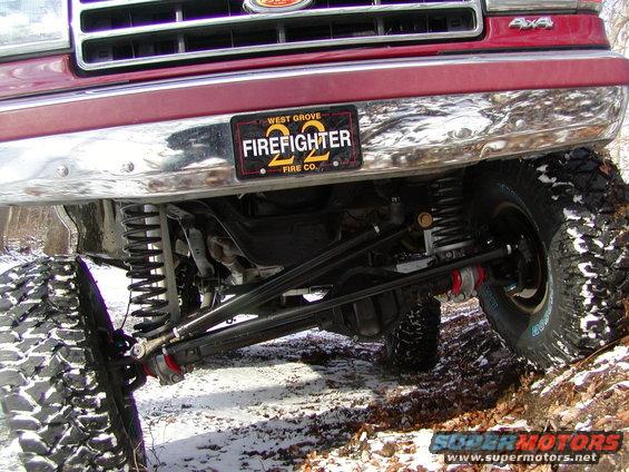 Front grille and bumper of a red Ford F-Series truck with a "Firefighter 22" license plate and off-road suspension