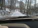 1991 Ford Bronco - View from inside a vehicle as it travels down a snow-covered road through a forest.