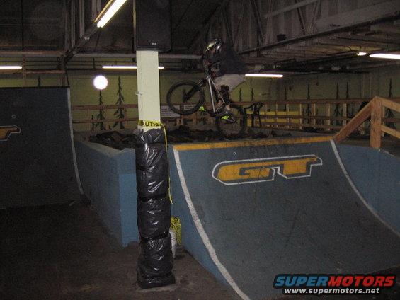 Person on a bicycle performing a trick on a ramp inside an indoor skatepark