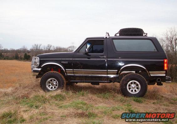 Black 1995 Ford Bronco side view with spare tire on roof rack