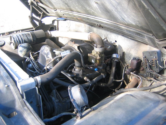 Engine bay with hoses, carburetor, and air filter visible