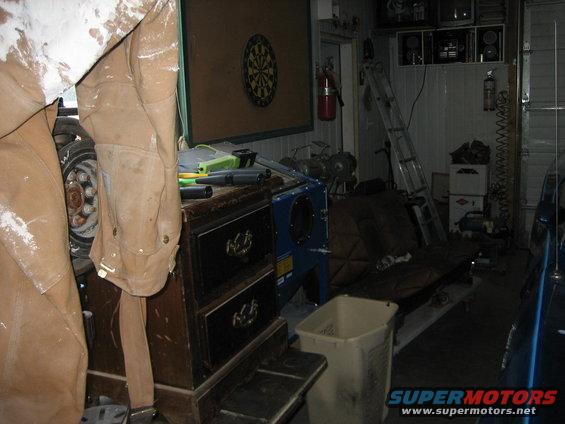 Garage interior with a dartboard, fire extinguisher, ladder, and various tools and furniture