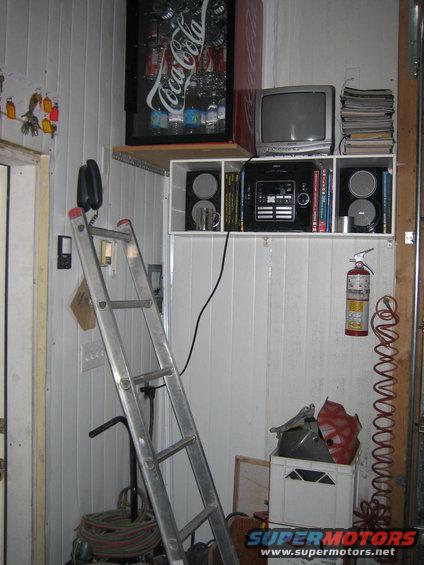 Garage interior with a Coca-Cola machine, TV, stereo, ladder, and fire extinguisher