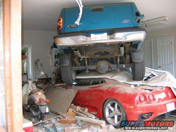 Blue 1991 Ford F-150 truck on top of red Ferrari, rear view