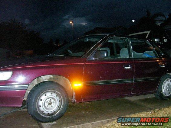 Maroon sedan side view with amber turn signal