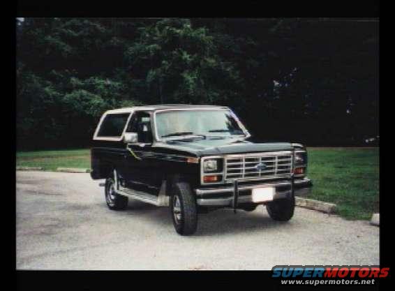 Black Ford Bronco parked on asphalt with trees in background
