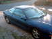 1994 Ford Probe - A blue coupe is parked on a gravel driveway, reflecting trees in its windows.
