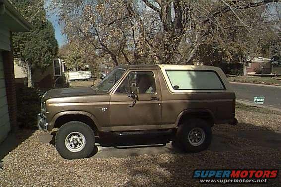 1980 Ford Bronco parked on gravel next to a house