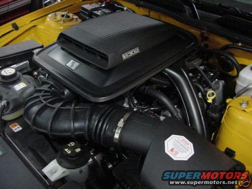 Yellow engine bay with black air intake system and "302" badge on engine cover