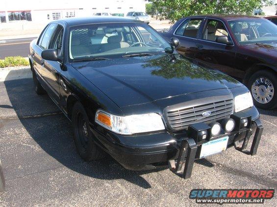 Black police car with push bar and spotlights, parked next to another car