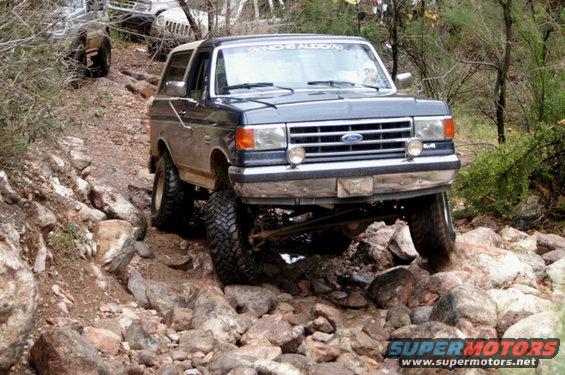 1991 Ford Bronco navigating a rocky trail, another vehicle visible in background