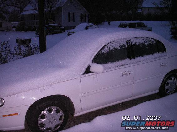 White sedan covered in snow, side view. Date stamp 02.01.2007
