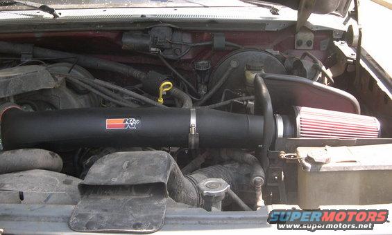 Engine bay with black K&N air intake system and red filter. Maroon paint visible