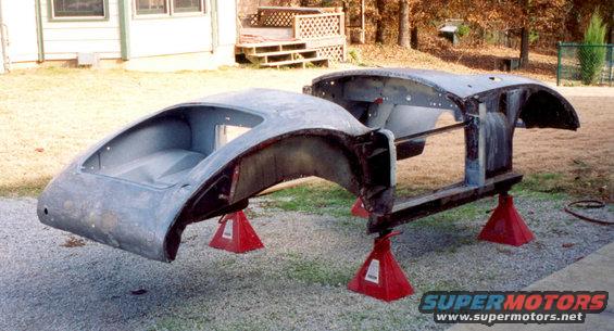 car body shell on red jack stands outside a house