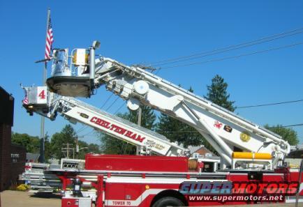 Red fire truck with extended white ladder and basket, American flag flying above