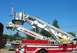 1989 Ford Bronco - A fire truck with an extended ladder is parked outdoors under a clear blue sky.