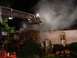 1989 Ford Bronco - Firefighters battle a house fire at night, with smoke billowing from the roof.