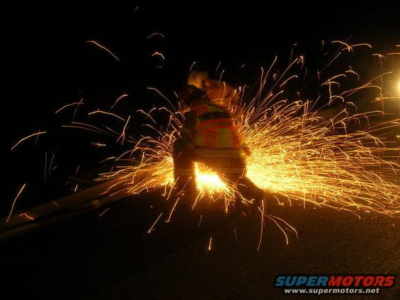 Person using angle grinder, creating shower of sparks at night