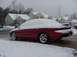 1998 Ford Taurus - A red sedan is parked outside a house, completely covered in snow.