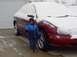 1998 Ford Taurus - A child stands next to a snow-covered 1998 Ford Taurus in front of a garage.