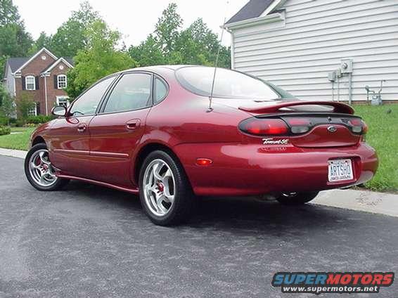 Red 1998 Ford Taurus SE sedan parked on asphalt, showing rear quarter panel and spoiler