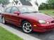 1998 Ford Taurus - A red 1998 Ford Taurus sedan is parked on the side of the road with houses in the background.