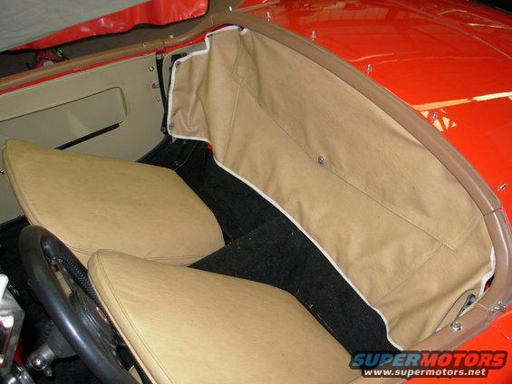 Tan interior of a 1959 MG A convertible with black carpet and a tan top boot
