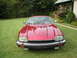 1992 Jaguar XJ-S - A red 1992 Jaguar XJ-S is parked on a manicured lawn with a house and trees in the background.