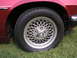 1992 Jaguar XJ-S - The mesh alloy wheel and fender of a red Jaguar XJ-S are visible.