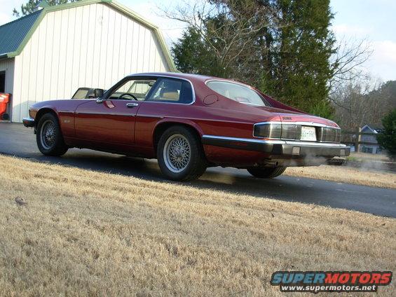 Red 1992 Jaguar XJ-S coupe parked on a driveway, rear view. Exhaust is smoking