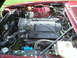 1992 Jaguar XJ-S - The engine bay of a red car reveals a Corvette engine, indicated by the prominent branding on the intake manifold.