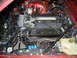 1992 Jaguar XJ-S - The engine bay of a red vehicle, showing a V8 engine with visible Jaguar branding on a component.