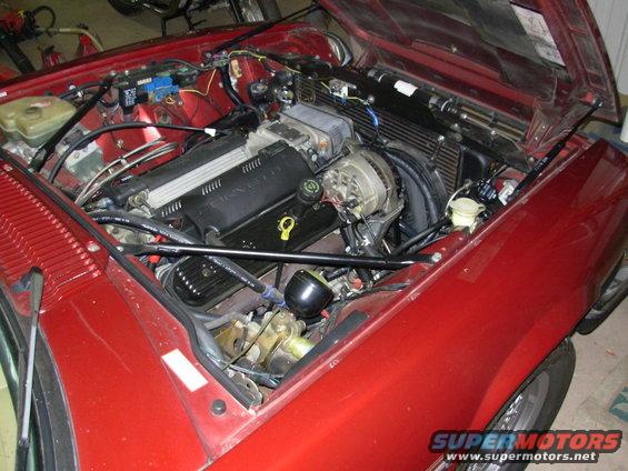 Red car's engine bay shows a V8 engine with a Corvette-branded valve cover