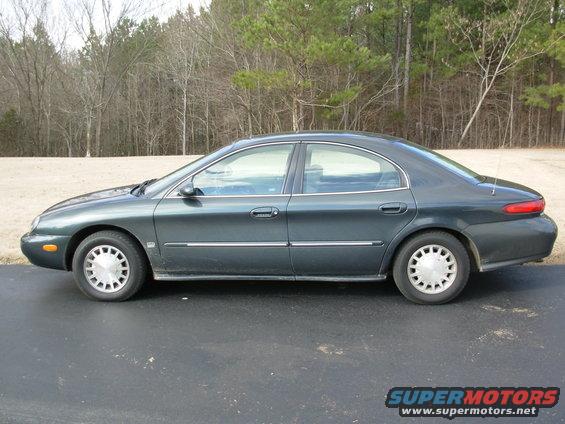 1999 Mercury Sable sedan, side view. Dark green paint, silver hubcaps