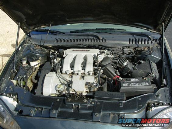 Car engine bay with V6 engine, air intake, and battery visible