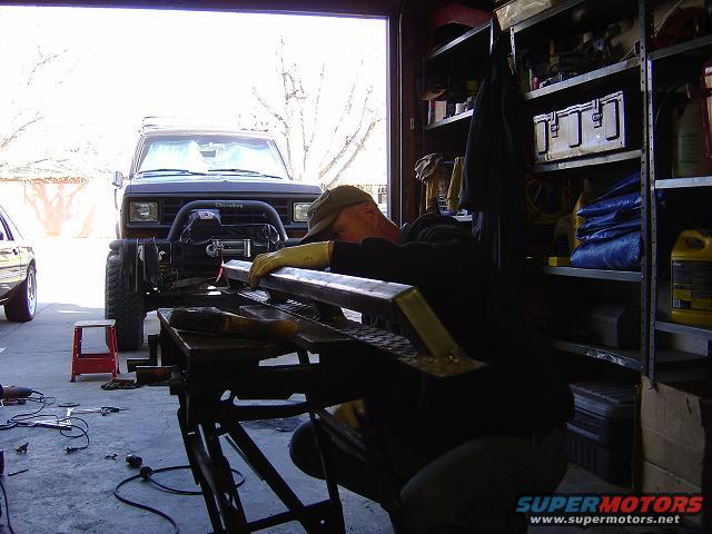 1986 Ford Bronco II in garage, front view, with man working on metal in foreground