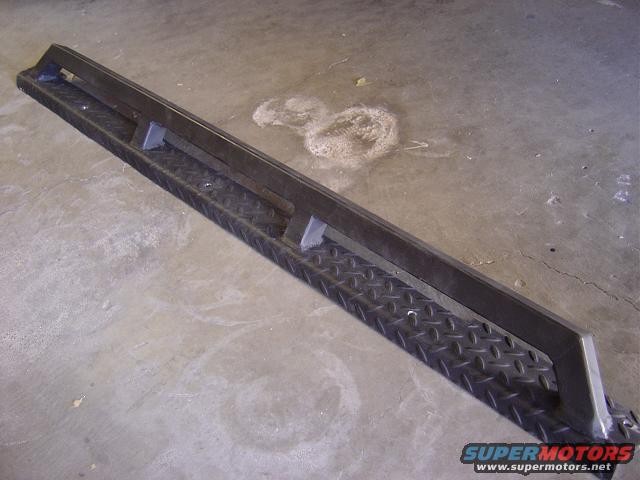 Diamond plate running board with a metal bar on top, on a concrete floor