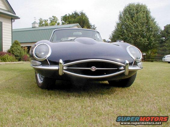 Dark blue 1967 Jaguar XKE convertible front view, chrome bumper, large headlights, on grass