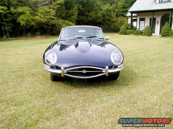 Dark blue 1967 Jaguar XKE coupe parked on grass in front of a house