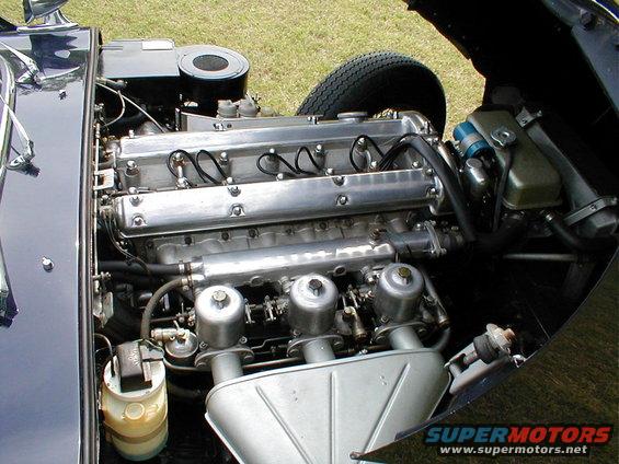 Dark blue 1967 Jaguar XKE engine bay with a six-cylinder engine, triple carburetors, and an air filter
