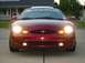 1998 Ford Taurus - Front view of a red Ford Taurus with its headlights illuminated.