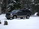 2003 Ford Excursion - A dark blue and tan Ford Excursion is parked in a snowy landscape, showing its 3/4 front view.