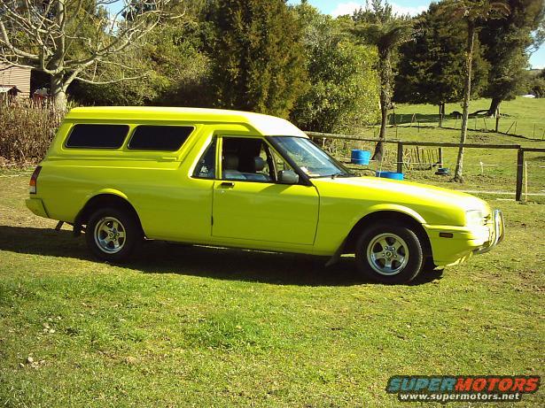 Lime green utility vehicle with a camper shell, side view. Watermark reads SUPERMOTORS.NET