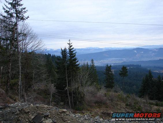Overcast sky above forested mountains and a valley, with power lines crossing the frame