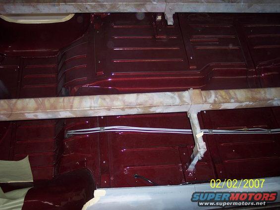 Underside of a car with dark red painted floor pans and metal support beams. Date stamp reads 02/02/2007