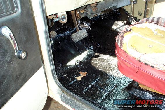Truck interior with black undercoating on floor, red seat, and chrome door handle