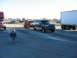 1952 Ford Pickup - A dark blue SUV from the 1990s tows a trailer with a red tractor, parked near other trucks.